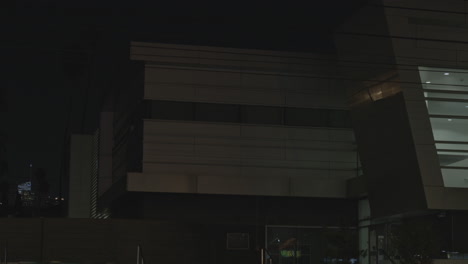 static shot of a local police station office building at night with some traffic movement in the foreground