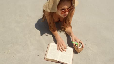 high angle view of caucasian woman in hat reading a book on the beach 4k