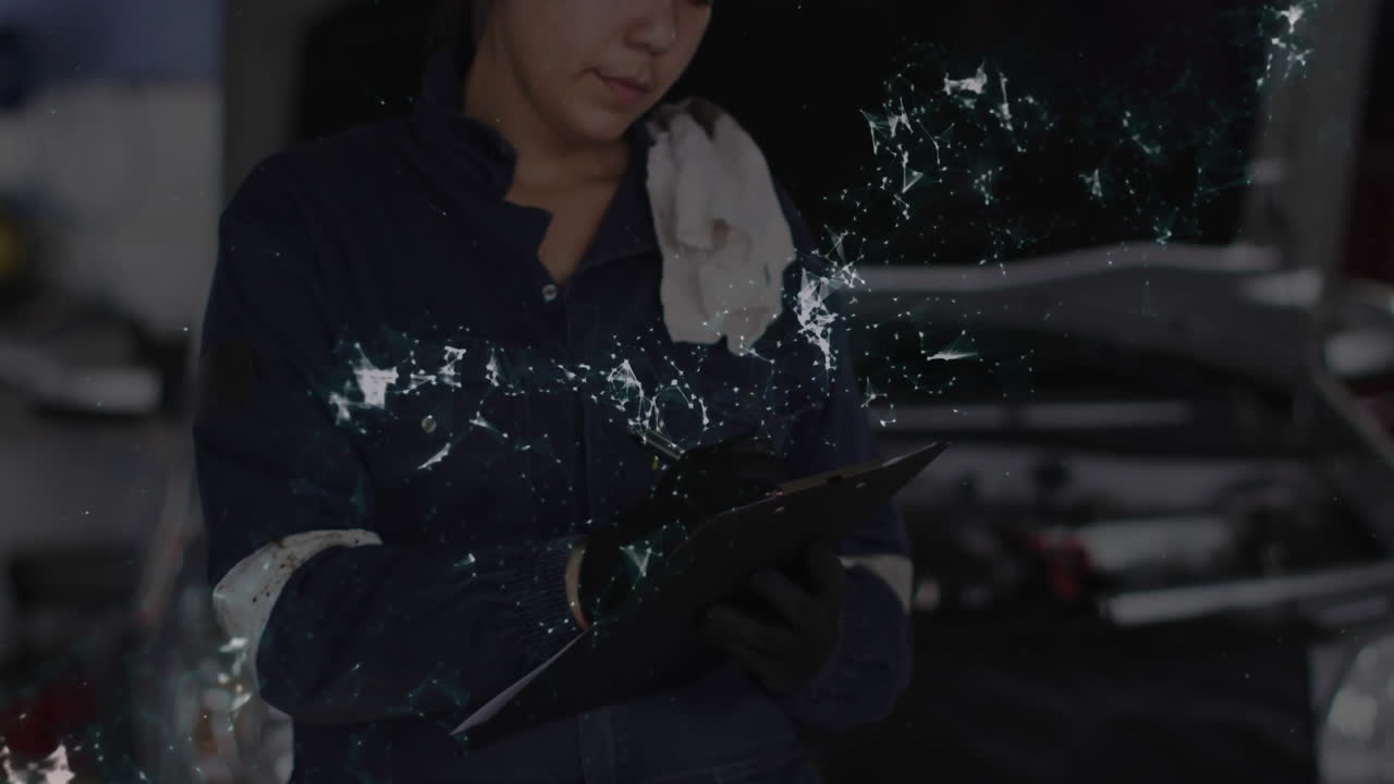 female automotive technician writing on clipboard in garage, with black gloves and network overlay