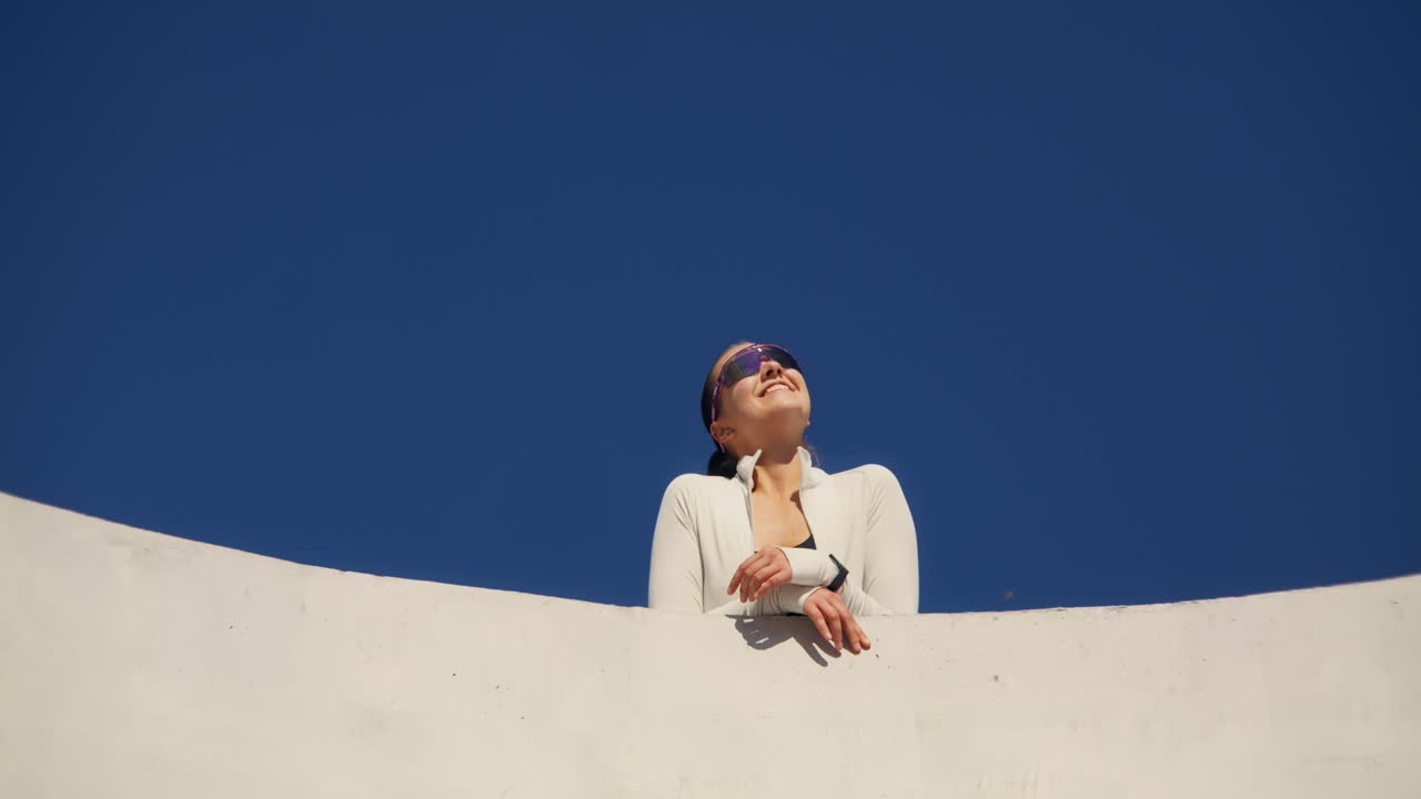 Woman with Sunglasses Looking Up at Blue Sky
