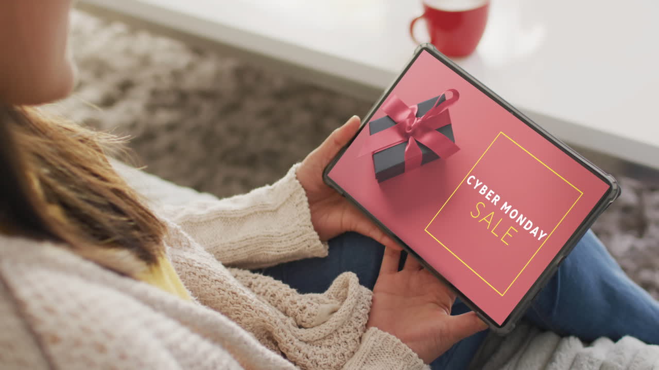 Mujer caucásica usando una tableta en casa para compras en línea, texto de Cyber Monday, cámara lenta.