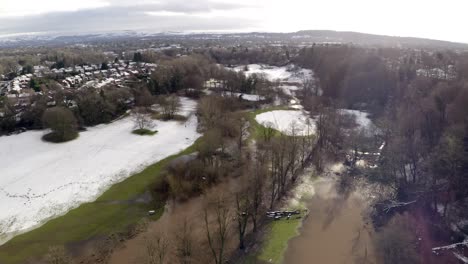 aerial footage from drone showing the river bollin in wilmslow, cheshire after heavy rain, showing burst banks and flooding surrounding area after rain storm