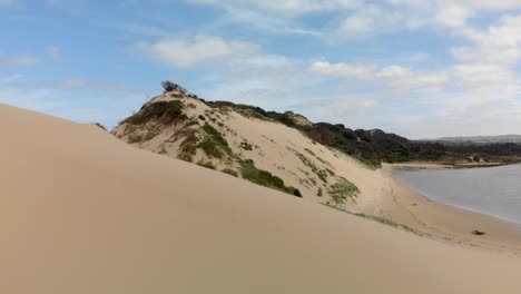 una antena de movimiento rápido hacia adelante de un sistema de desembocadura de río y moviéndose sobre las dunas de arena para revelar el océano
