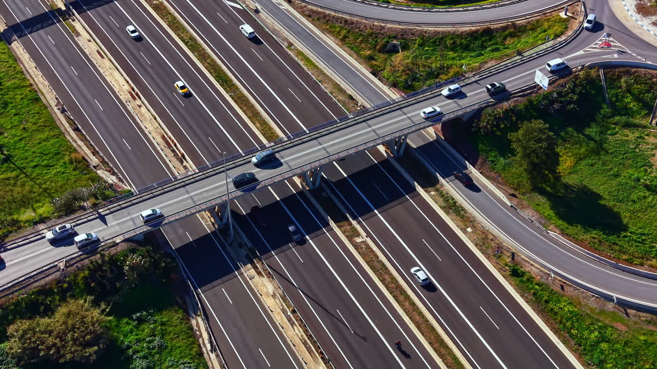 Il traffico scorre su un'autostrada trafficata con più corsie e veicoli che viaggiano in entrambe le direzioni sotto un cielo sereno durante il giorno.