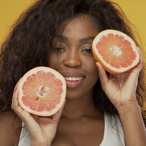 Cheerful-black-lady-showing-halves-of-grapefruit