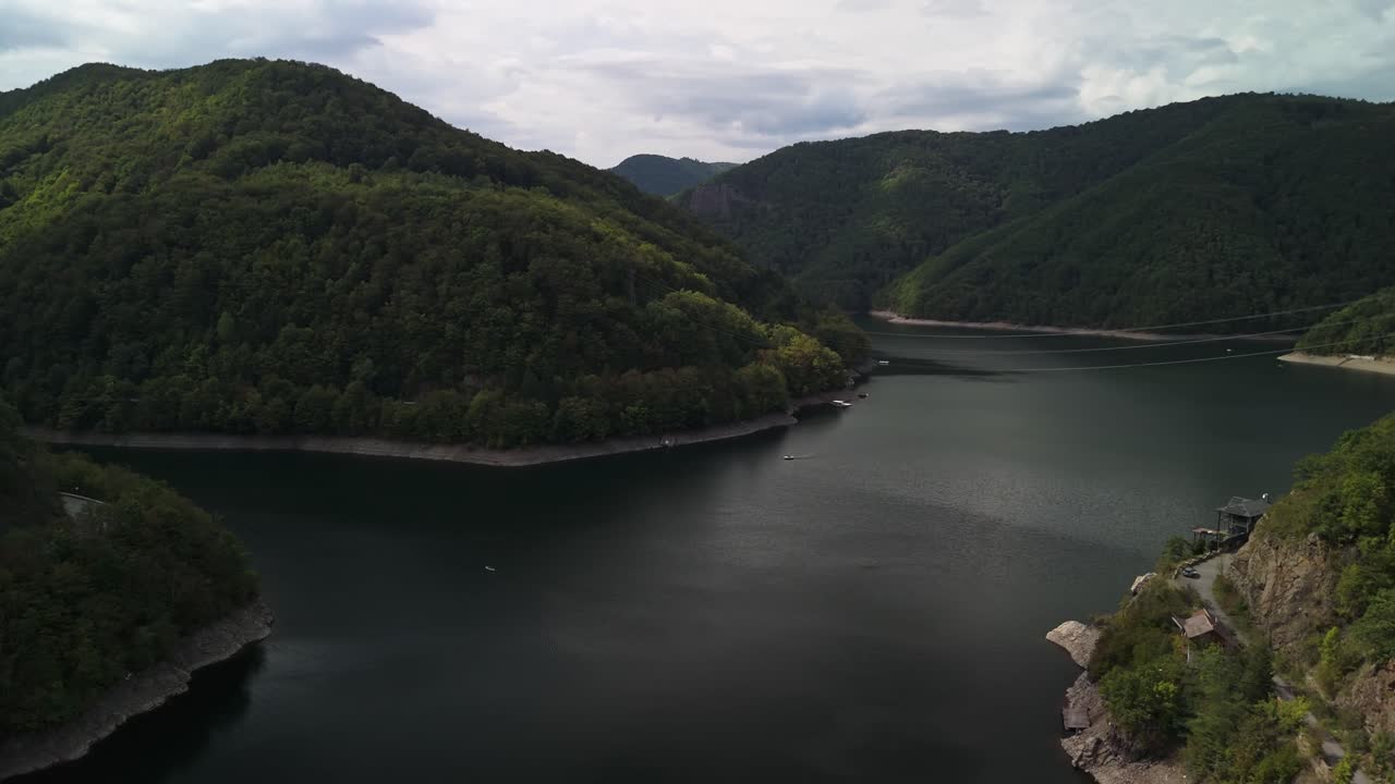 Spectacular aerial view from the Tarnița Lake and surrounding green mountains on a cloudy autumn day in Romania