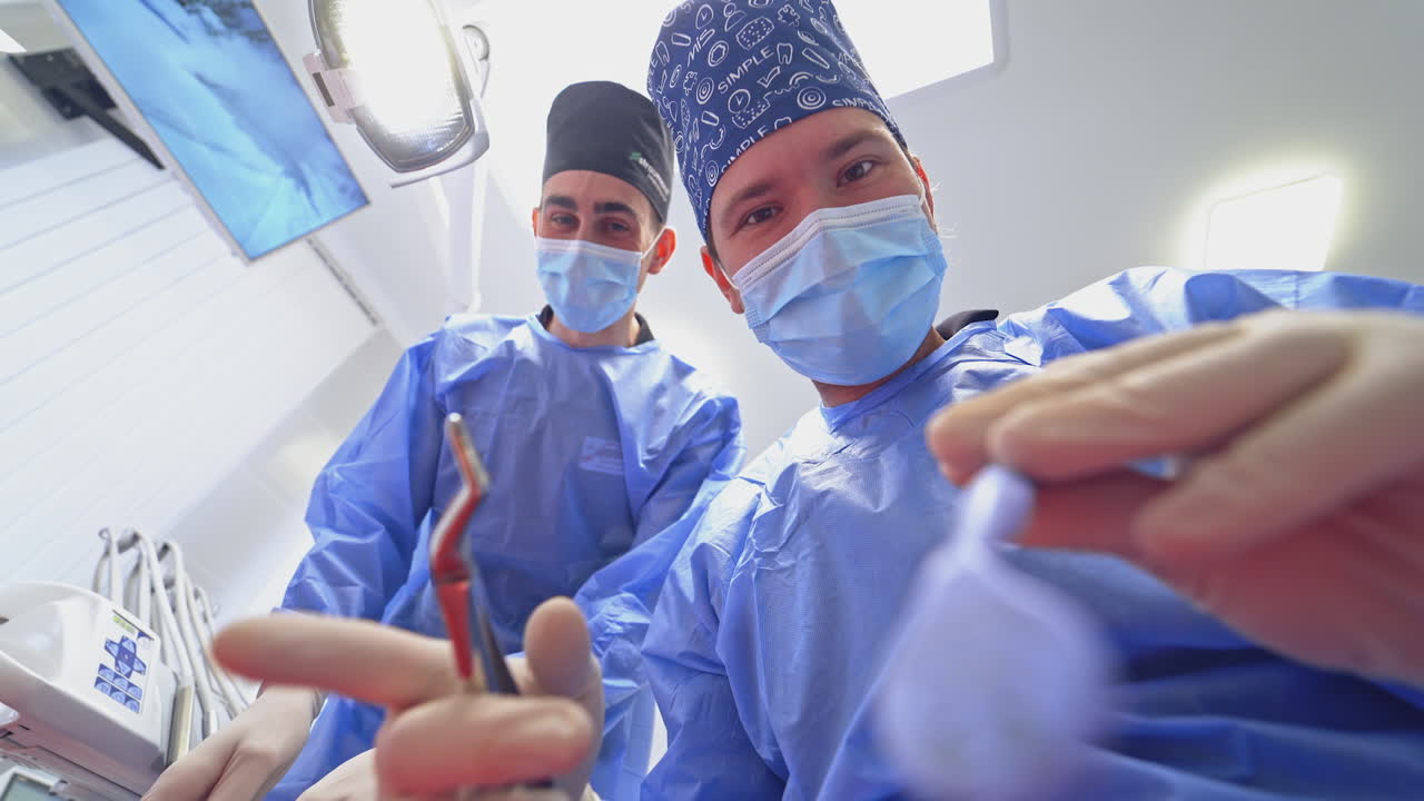 Professional dentist treats tooth. Assistant helps stomatologist in dental clinic. Doctors use modern methods of treatment. View from below.