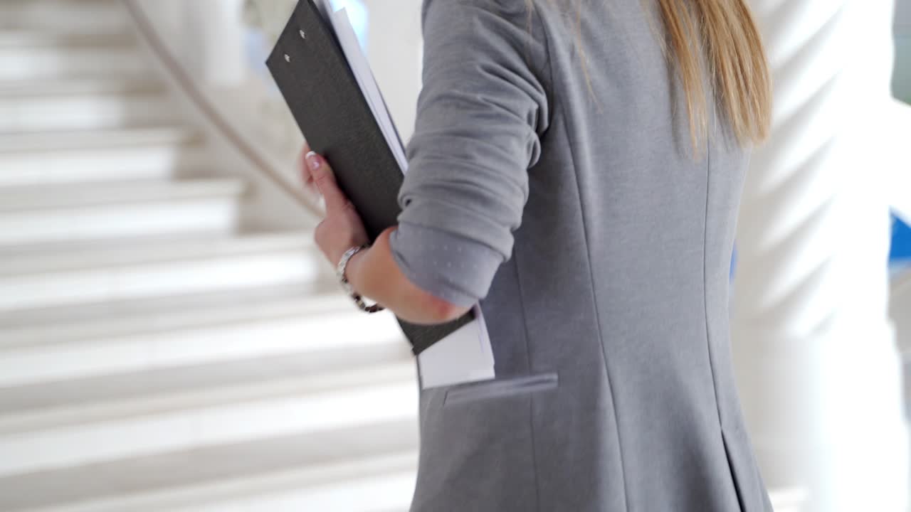colleague with folders in her hands is running to the office on the stairs. Late for work