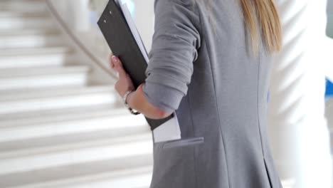 colleague with folders in her hands is running to the office on the stairs. late for work