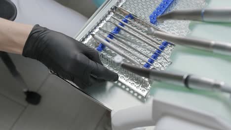 preparation for the dental procedure. surgery tools. multiple surgery tools on the table in operating room. scrub nurse hands in rubber gloves. modern dental concept.