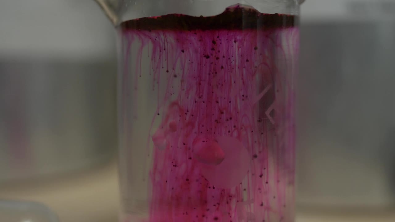Esperimento chimico con liquido rosa in becher