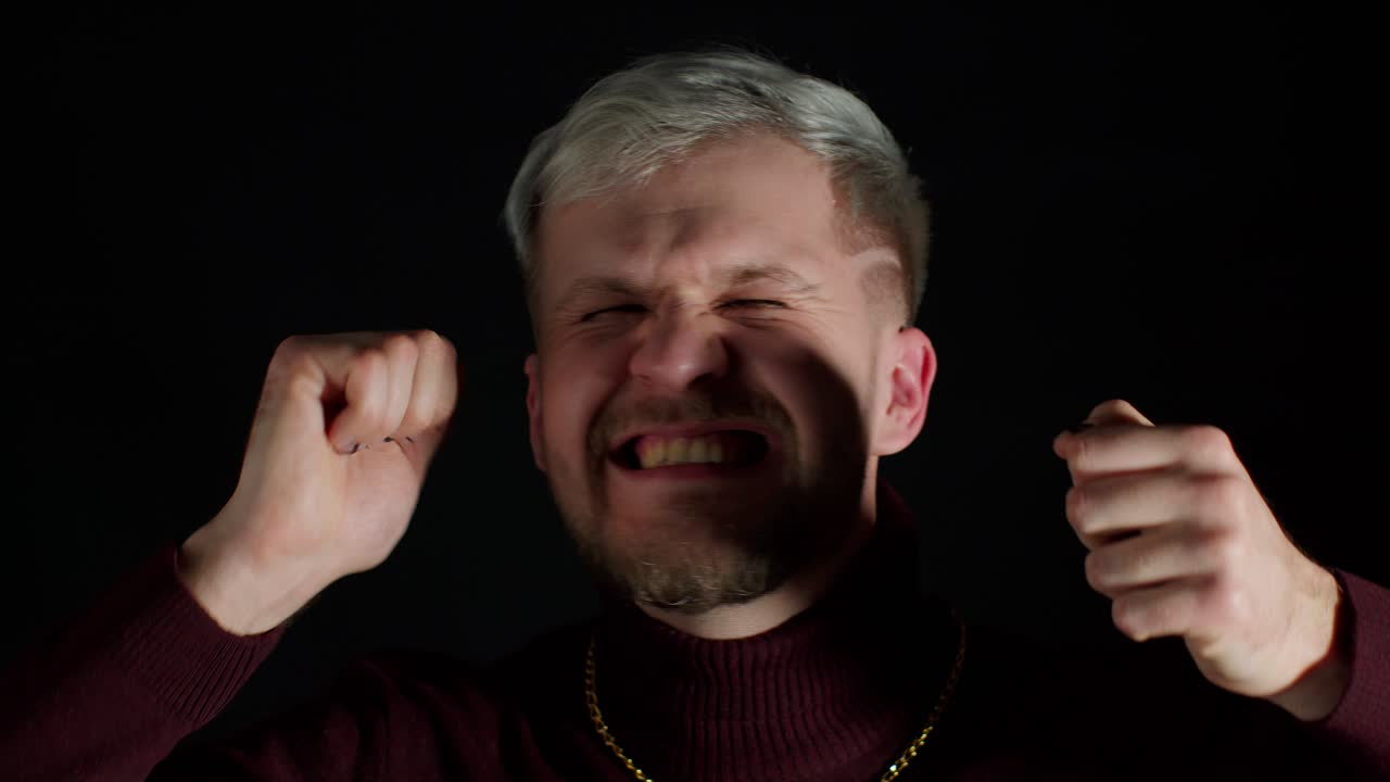 파란 눈과 수염을 가진 젊은 남자가 웃고 웃으며 행복하고 흥분한 모습으로 보입니다.