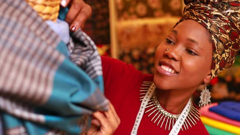 tanzanian woman with snake print turban over hear working in fabrics shop