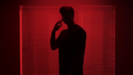 silhouette of a man in a red-lit room