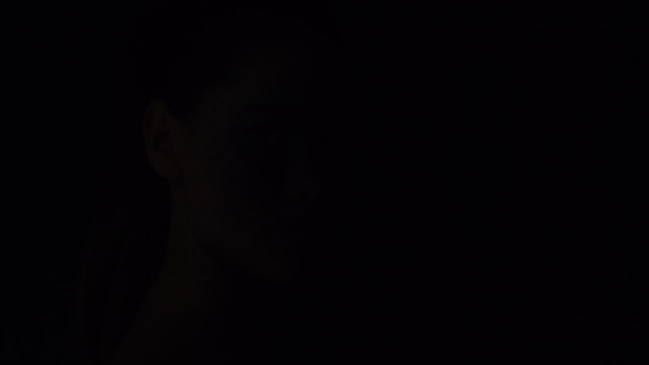 retrato de una mujer hermosa con maquillaje de pintura facial azul buscando arte corporal exótico en una artista femenina atractiva expresión creativa luz desvaneciéndose en un fondo oscuro