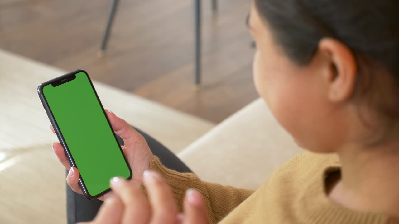 크로마 키를 들고 있는 흑인 여성의 뒷모습, 녹색 화면 스마트폰, 만지거나 스와이프하지 않고 콘텐츠를 보는 모습.