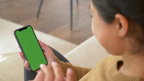 vista trasera de la morena sosteniendo la llave de croma pantalla verde teléfono inteligente viendo contenido sin tocar o deslizar. aparatos y conceptos de personas contemporáneas.