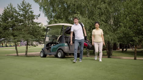 Asian-people-collecting-golf-clubs-from-golf-cart-and-walking-to-the-field