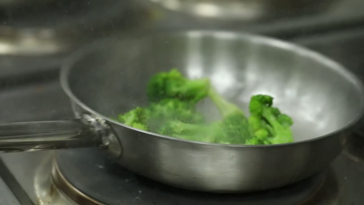A Chief cooks broccoli on a grill close up shot, insert shot