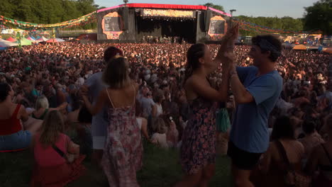 vibrant outdoor music festival with people dancing on a grassy hill