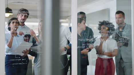 Gruppe-Von-Geschäftsleuten-Beim-Brainstorming,-Schreiben-Von-Ideen-Auf-Glas-Whiteboard,-Kollegen,-Die-An-Problemlösungslösungen-Arbeiten-Und-Strategie-Teamarbeit-In-Bürobesprechung-4k-Diskutieren