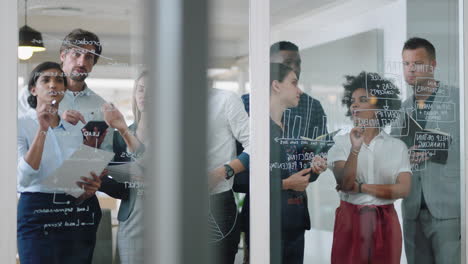 group of business people brainstorming writing ideas on glass whiteboard colleagues working on problem solving solution discussing strategy teamwork in office meeting 4k