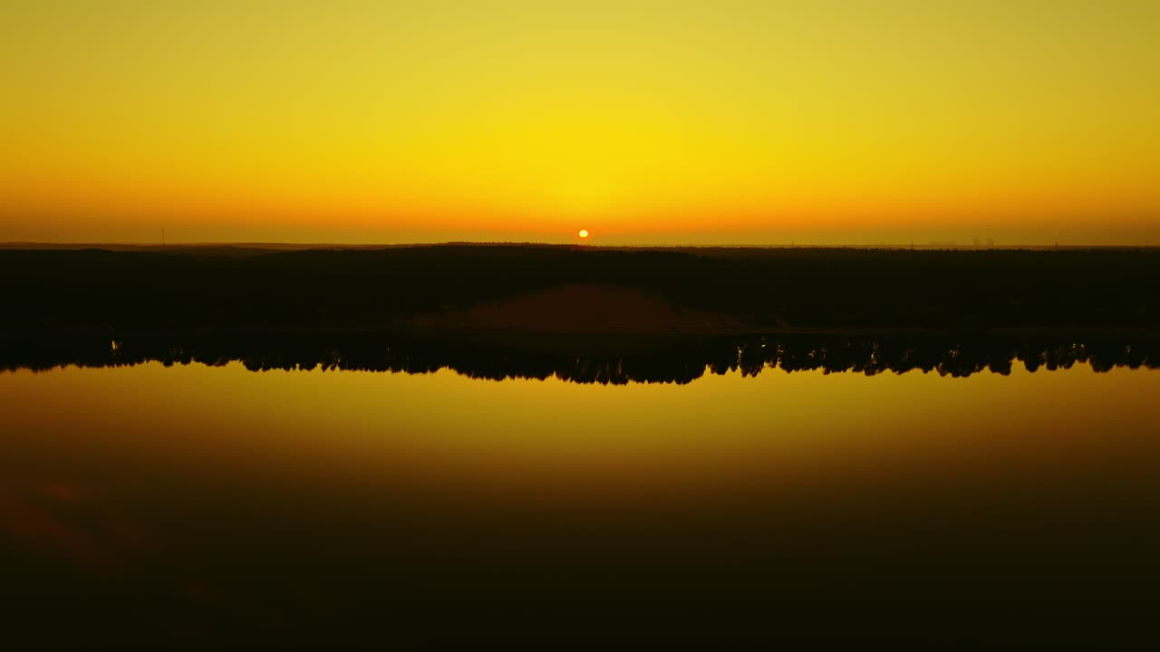 Calm spring sunrise mirrors in river as drone approaches Latvia’s White Dune