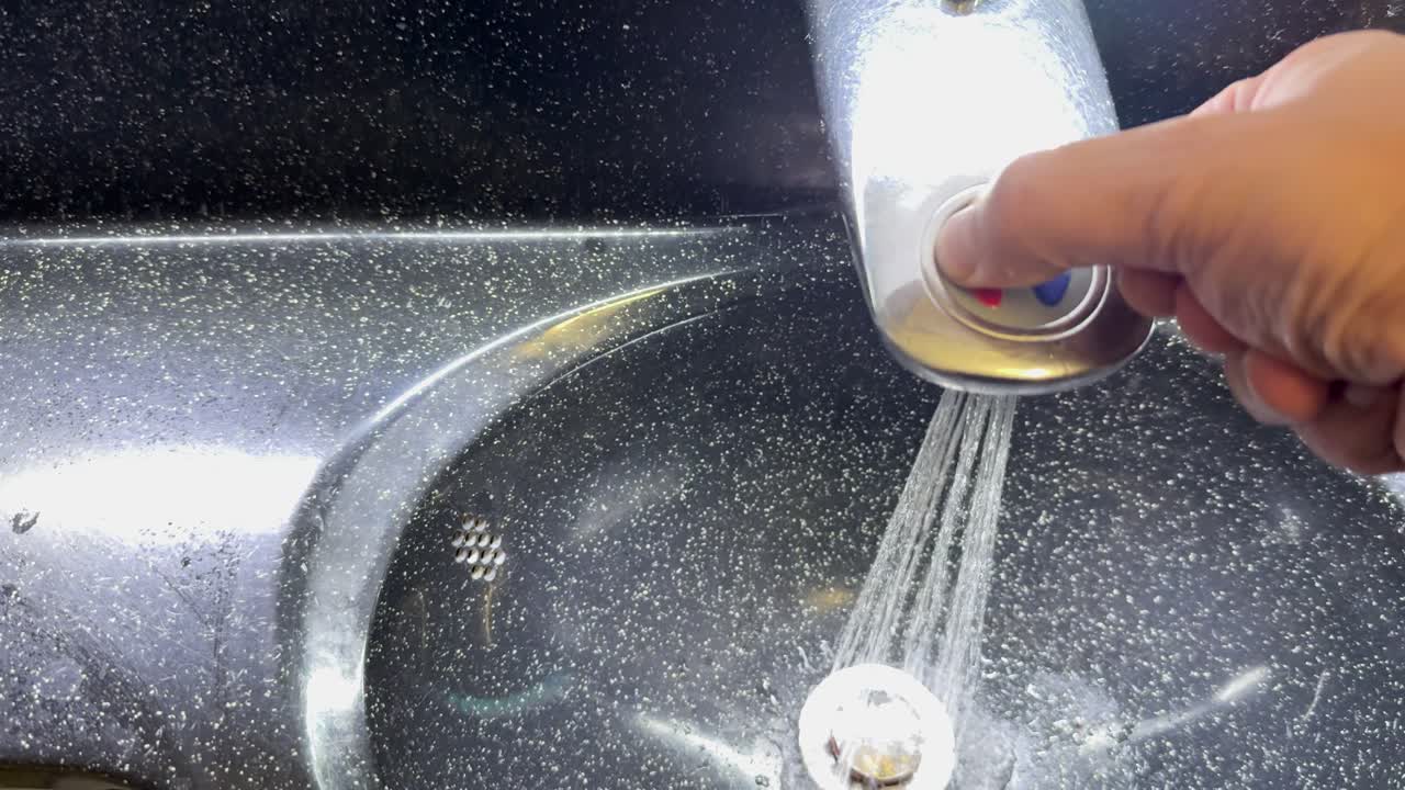 Person washes hands under running water in airplane lavatory, close-up, bright artificial lighting