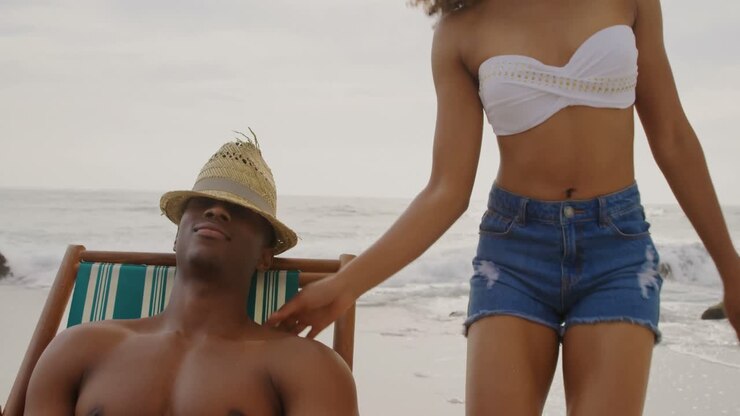 Vista frontale di coppia afroamericana che si diverte insieme sulla spiaggia 4k