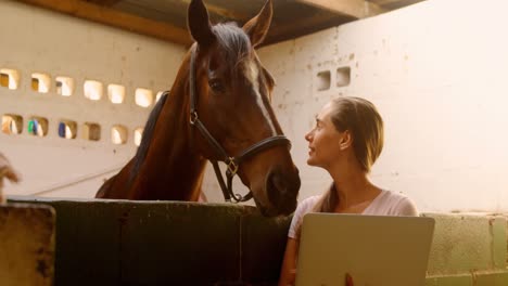 woman standing with horse using laptop 4k