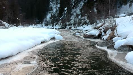 Kleines-Zugefrorenes-Flussufer-In-Verschneiter-Landschaft-Im-Winter