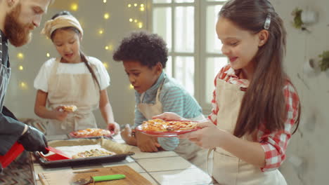 niña disfrutando del olor de la pizza en la clase magistral de cocina