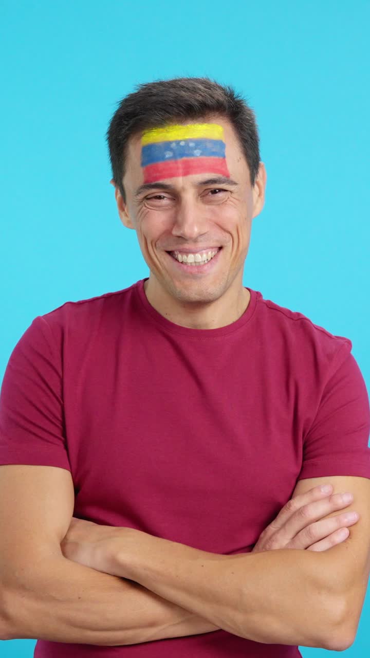 Man standing with venezuelan flag painted on face smiling