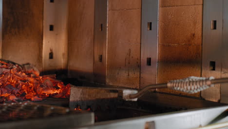 raking coals into a wood fired grill