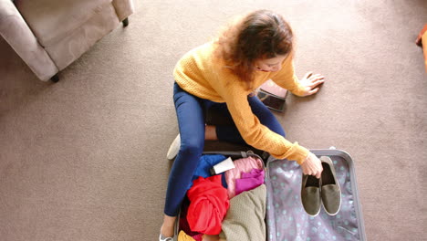 caucasian woman packing suitcase on floor at home, copy space, slow motion