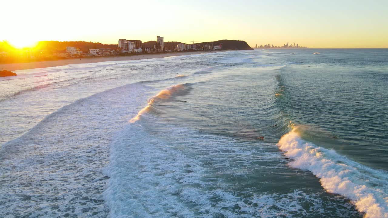 Veduta aerea di surfisti che cavalcano le onde sulla spiaggia all'alba - Spot per il surf a Palm Beach, Gold Coast, QLD, Australia