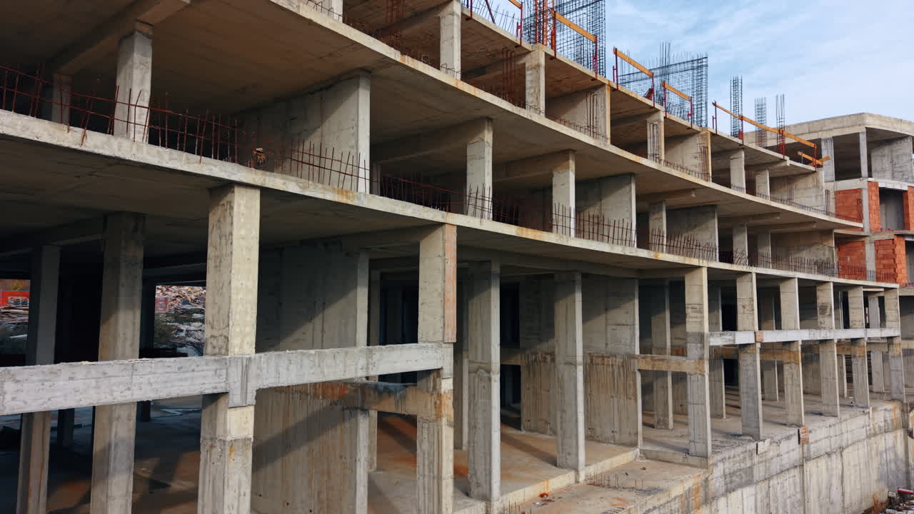 Flight along the frame of the three-storied building. A crane towers over the construction at backdrop