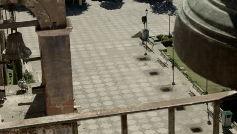 church bells mounted in high tower in the public square of a small mexican town, that can be heard by the surrounding community