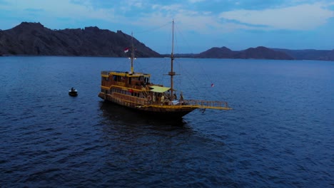 phinisi boat sailing on indian ocean at sunset in padar, east nusa tenggara, indonesia