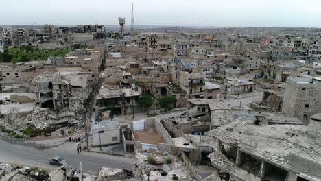 calles de una ciudad siria con coches conduciendo en una carretera y gente caminando. algunos de los edificios todavía están en ruinas después de la guerra civil hace 10 años - vista aérea con un dron 4k