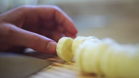 slow motion shot of someone using a knife to cut a ripe yellow banana into small slices