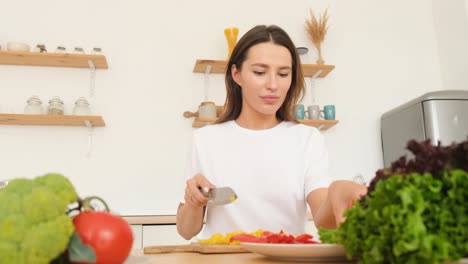 young woman slicing red bell pepper on a white cutting board in bright home kitchen young woman slicing red bell pepper on a white cutting board in bright home kitchen preparing ingredients for a healthy vegetable meal with a modern minimalist setup