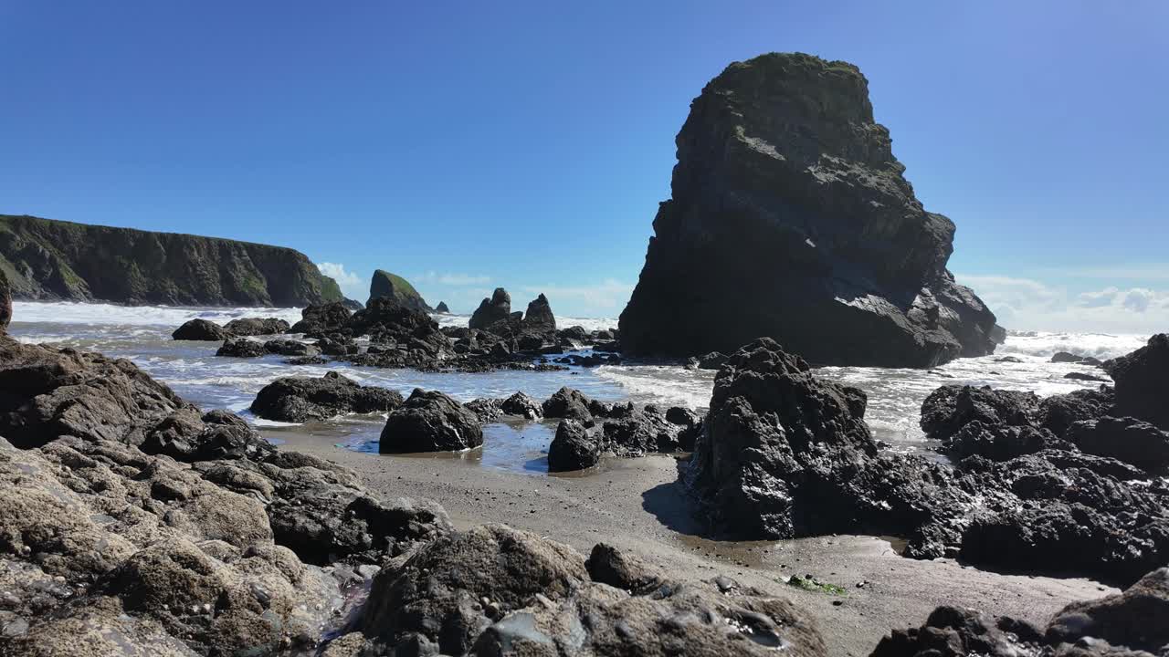 바다 스프레이와 봄의 조류가 워터포드 아일랜드의 발리드웨인 해변의 바위 해변에 들어오고 있습니다.