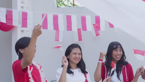 young women and men holding indonesia flags to commemorate indonesian independence day, august 17.