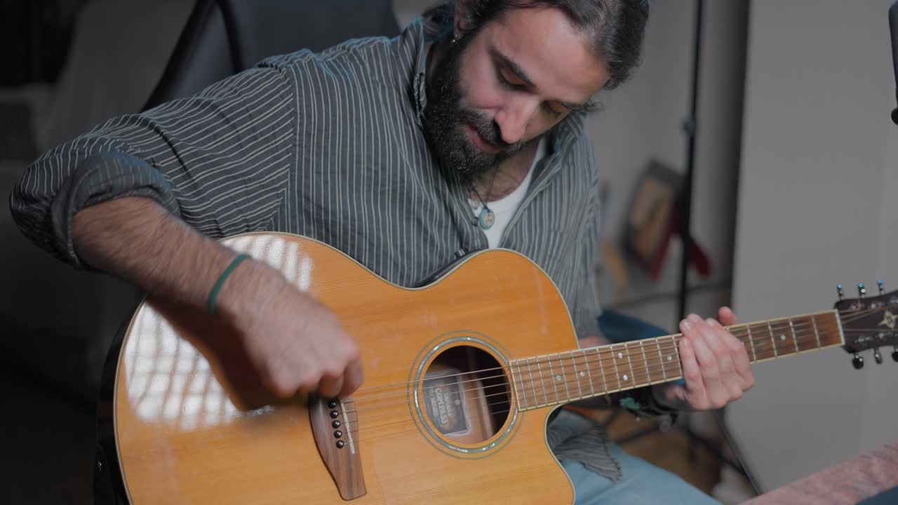 hombre tocando la guitarra acústica en el estudio casero