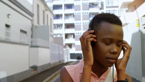 Woman-listening-music-on-headphones-while-walking-in-city-street-4k