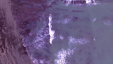 sea waves, coast and rocks aerial vertical point of view of asturias beach on a cloudy winter morning drone point of view