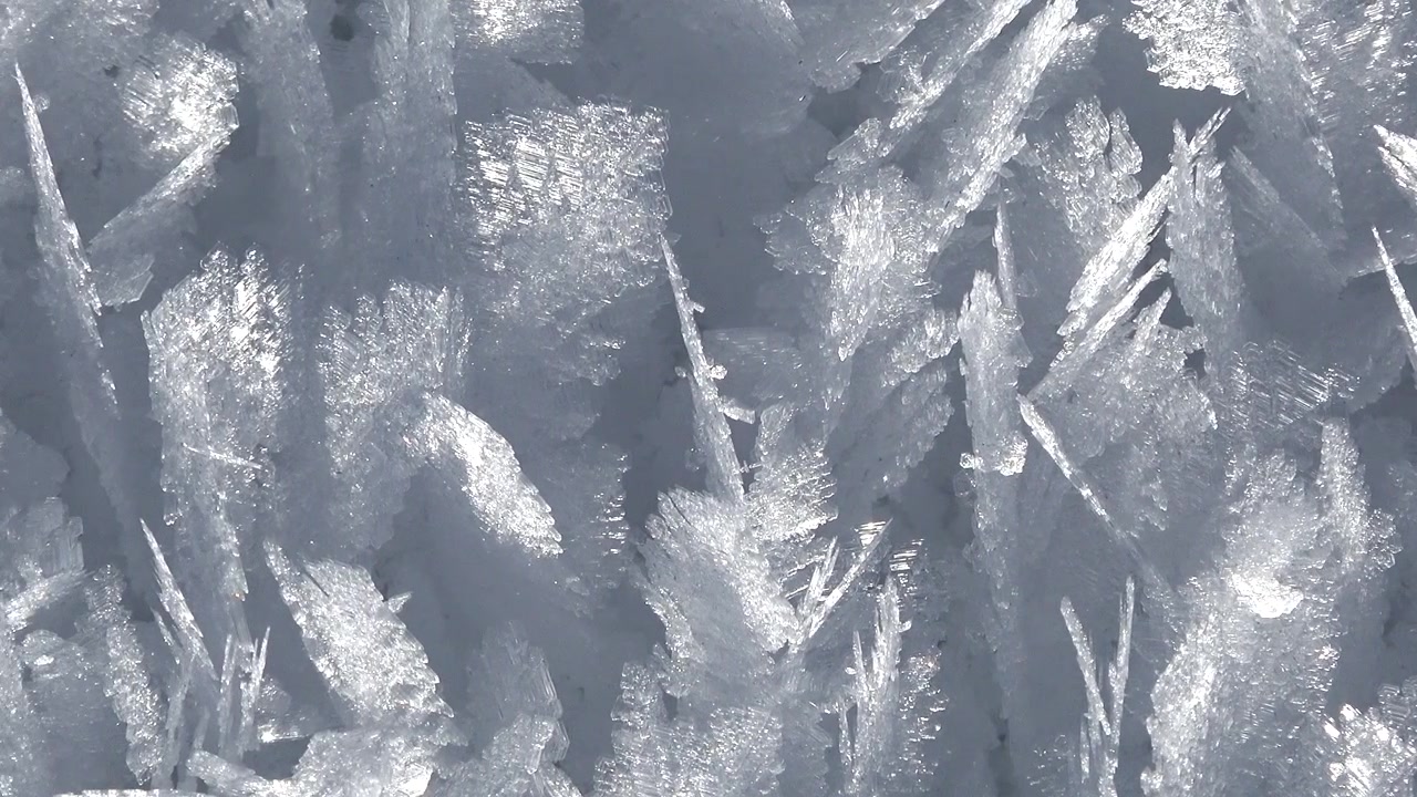 Primo piano di intricati cristalli di ghiaccio che si formano su una superficie ghiacciata