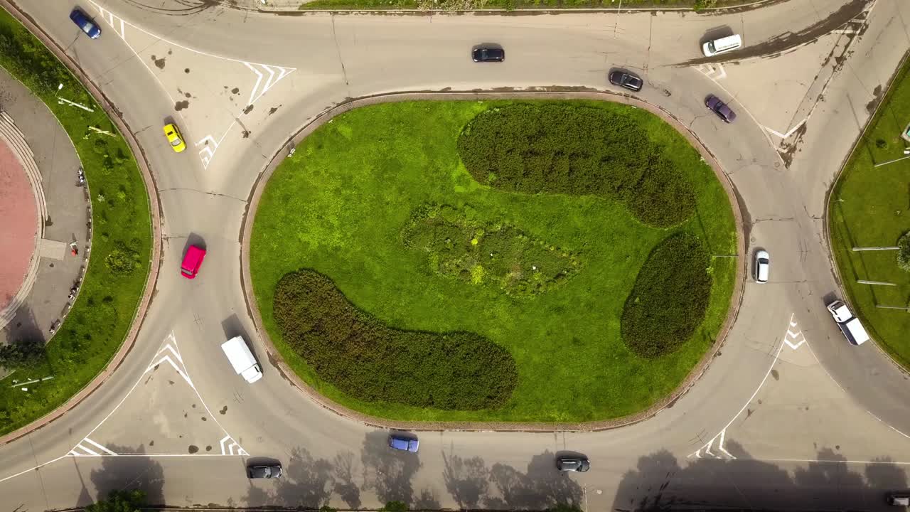 vista aérea de arriba hacia abajo de la intersección de la calle de la rotonda con el tráfico de coches en movimiento.