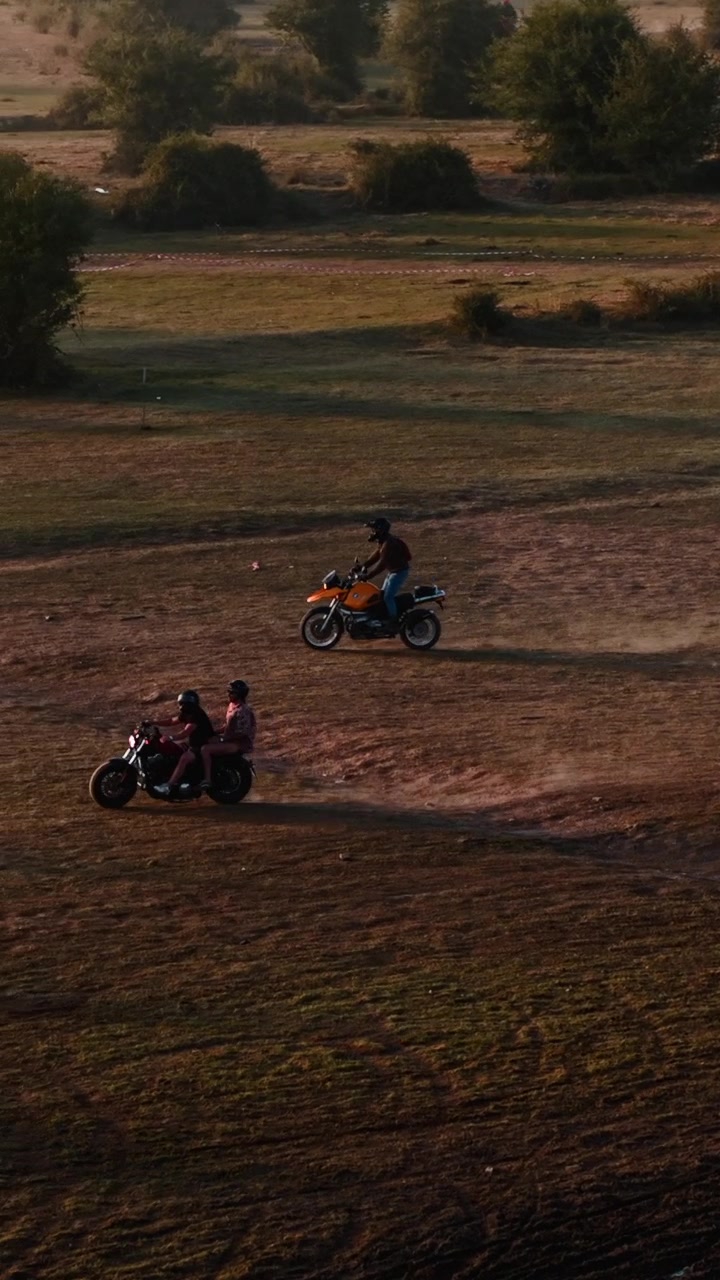 Motociclisti che attraversano un campo aperto al tramonto